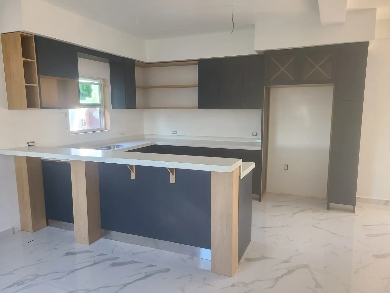 Cocina integral a la medida con isla, barra de cuarzo y muebles en tonos azul marino y madera