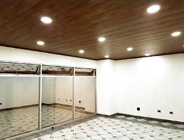 Local comercial remodelado con plafón de madera, luminarias empotradas y canceles de vidrio